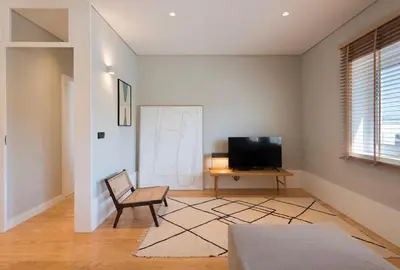 a living room with a chair and a television at Ceuta 33 Apartment in Porto