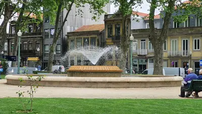 a fountain in a park with a person sitting on a bench at Marques Garden with PARKING in Porto