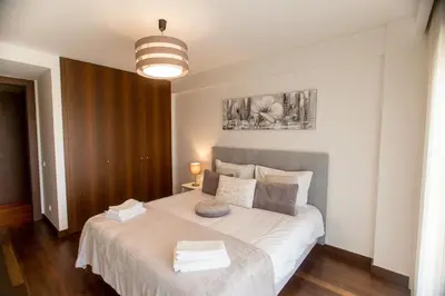 a bedroom with a bed with white sheets and a lamp at Afurada premium apartment by Porto City Hosts in Vila Nova de Gaia