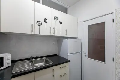 a kitchen with white cabinets and a sink and a refrigerator at Casa da Alegria- Downtown by Oporto Soul in Porto