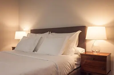 a bed with white pillows and a nightstand with two lamps at B The Guest Downtown in Porto