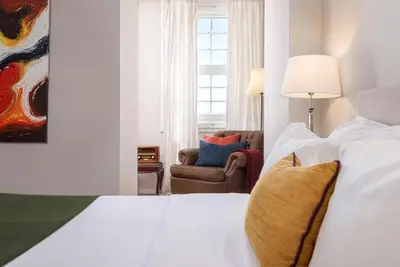a bedroom with a bed and a chair and a window at B The Guest Downtown in Porto