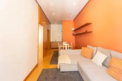 a living room with a white couch and an orange wall at Porto by the River 1 in Porto