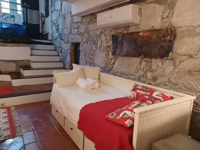 a bed in a room with a stone wall at Cosy apartment in Porto city centre – 50 sqm with parking in Porto