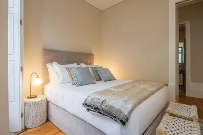 a bedroom with a large white bed with blue pillows at Tailor's Apartment in Porto