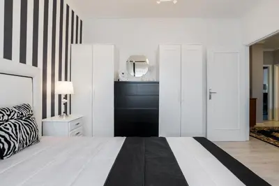 a white bedroom with a black and white bed and a mirror at Metropolitan Gaia-Porto in Vila Nova de Gaia