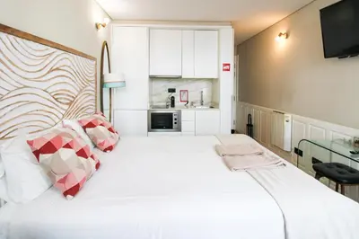 a bedroom with a bed and two chairs and windows at Charming Studio in Historic Downtown in Porto