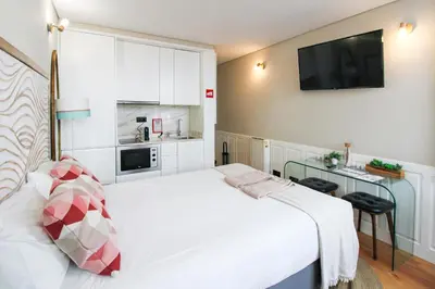 a bedroom with a white bed and a kitchen at Charming Studio in Historic Downtown in Porto