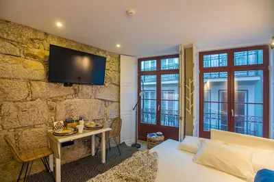 a bedroom with a bed and a tv on a stone wall at Oldtown Studio in Porto