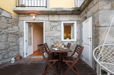 a patio with a wooden table and chairs on a stone wall at LovelyStay - Porto Peaceful Living W/ Backyard in Porto
