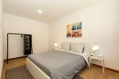 a white bedroom with a bed and two lamps at Eiffel Porto in Porto