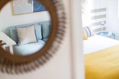 a mirror reflection of a blue couch in a bedroom at Sweet Flat 4Two in City Center, Balcony & Air Conditioning in Porto
