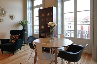 a dining room table with chairs and a vase with flowers at FLH Porto Trendy Flat in Porto