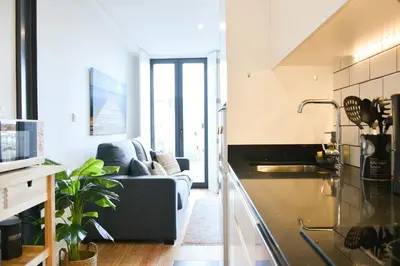 a living room with a couch and a kitchen at Comfortable&Central w/balcony-9 min walk Trindade in Porto