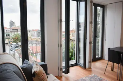 a living room with large windows and a couch at Comfortable&Central w/balcony-9 min walk Trindade in Porto