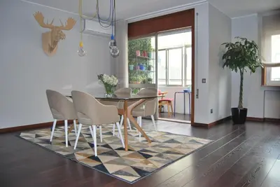 a dining room with a table and chairs on a rug at Suite Camões in Porto