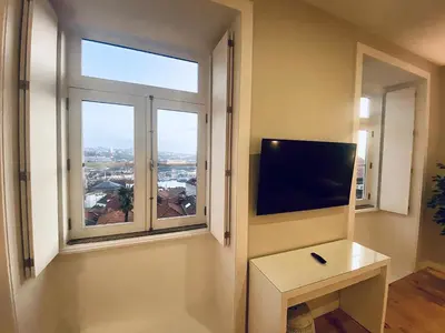 a room with a large window with a flat screen tv at Vitoria's Terrace Apartments in Porto