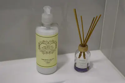 a bottle of moisturizers next to a vase with sticks at A&R Bolhão Apartment in Porto