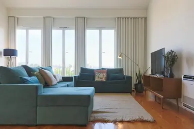 a living room with a blue couch and a television at Batalha Mezzanine Penthouse in Porto