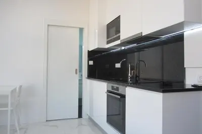 a kitchen with white cabinets and black appliances at VB Porto City Studio, by Flat in Porto in Porto