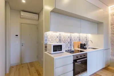 a kitchen with white cabinets and a microwave at Luz & Alegria Place! in Porto