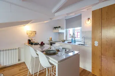a kitchen with a white counter and chairs in it at Beautiful Loft Downtown Porto in Porto