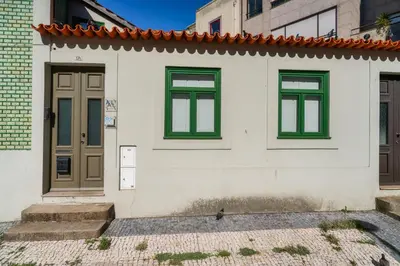 a white house with green windows and a door at Lovely Nest Downtown Porto in Porto