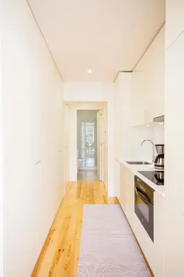 a kitchen with white cabinets and a wooden floor at São Bento Hill View in Porto