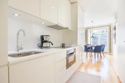 a kitchen with white cabinets and a table with blue chairs at São Bento Hill View in Porto
