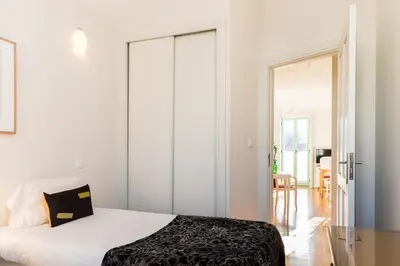 a bedroom with white walls and a bed with a black blanket at VIVA Ilda's Home in Porto