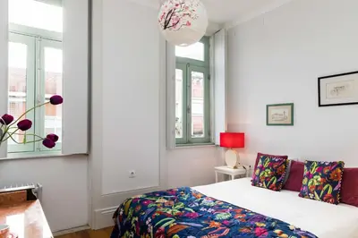 a bedroom with a bed and two windows at VIVA Ilda's Home in Porto