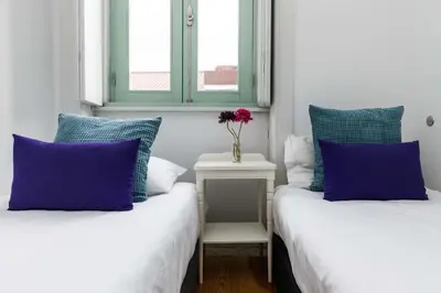two beds with blue and white pillows in a room at VIVA Ilda's Home in Porto