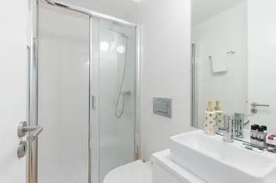 a white bathroom with a shower and a sink at Loureiro Villas in Porto