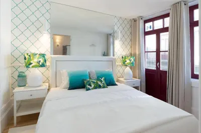 a bedroom with a white bed with blue pillows at Loureiro Villas in Porto