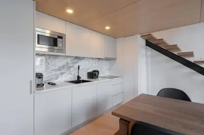 a kitchen with white cabinets and a wooden table at Loft Douro Cais da Fontaínha in Vila Nova de Gaia