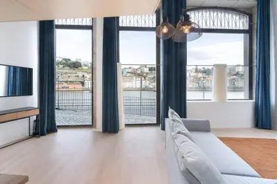 a living room with a couch and a tv and windows at Loft Douro Cais da Fontaínha in Vila Nova de Gaia