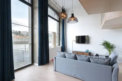 a living room with a couch and large windows at Loft Douro Cais da Fontaínha in Vila Nova de Gaia