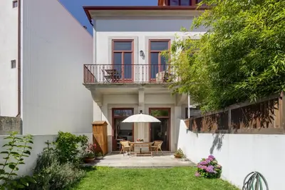 a white house with a table and an umbrella at Oporto MyWish City Central Apartment with Private Garden in Porto