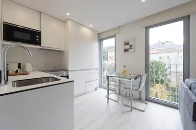 a kitchen with white cabinets and a table and a window at LovelyStay - Modern Loft with Gym & Free Parking minutes away from CBD in Porto