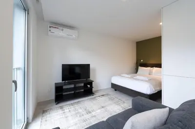 a bedroom with a bed and a couch and a tv at LovelyStay - Modern Loft with Gym & Free Parking minutes away from CBD in Porto
