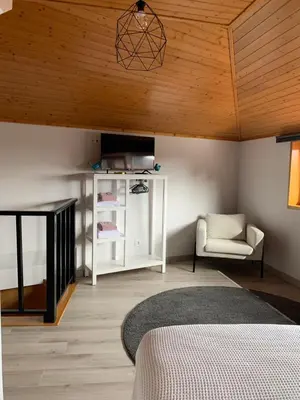 a bedroom with a bed and a chair and wooden ceilings at BF Suites & Apartments in Porto