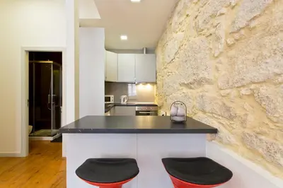 a kitchen with a stone wall and a counter with stools at Casas de Vera Cruz in Porto