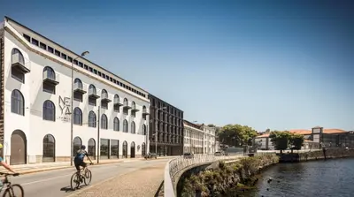 two people riding bikes down a street next to a river at NEYA Porto Hotel in Porto