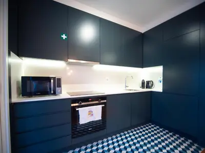 a kitchen with dark blue cabinets and a microwave at Oporto City View - Alves da Veiga in Porto