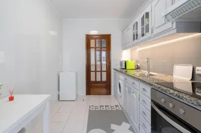 a white kitchen with a sink and a refrigerator at GuestReady - Modern 2BR Flat in Vila Nova de Gaia in Porto