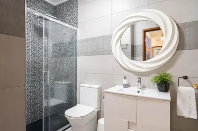 a bathroom with a toilet and a shower and a mirror at GuestReady - Modern 2BR Flat in Vila Nova de Gaia in Porto