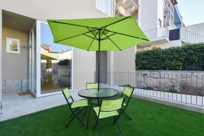 a table and chairs with a green umbrella at Duque - Guest House in Porto