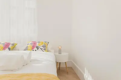 a white bedroom with a bed and a side table at Vibrant Host - Heroismo's Metro in Porto