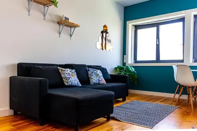 a living room with a black couch and a window at Guest H4U - Porto Batalha City Center in Porto