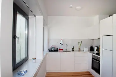 a kitchen with white cabinets and a window at Guest H4U - Porto Batalha City Center in Porto